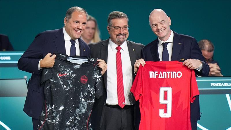 FIFA-Präsident Gianni Infantino (r) präsentiert mit Vizepräsident Victor Montagliani (l) und Kanadas Fußballchef Peter Augruso ein kanadisches Nationaltrikot mit seinem Namen.