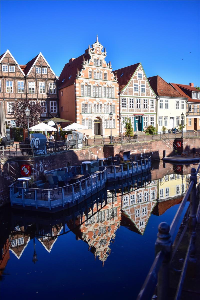 Fachwerkhäuser im Stader Hansehafen spiegeln sich im Wasser.