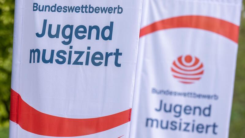 Fahnen mit dem Logo des Talentwettbewerbs „Jugend musiziert“ wehen im Wind.