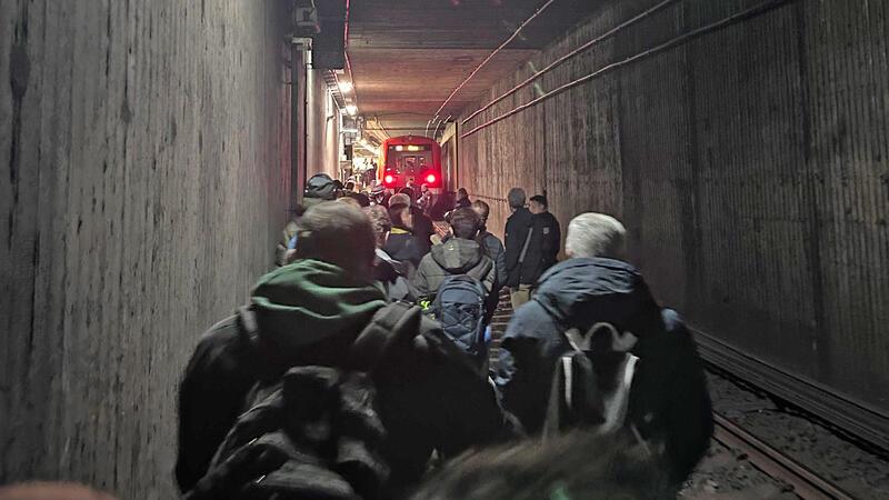 Fahrgäste gehen durch einen Tunnel. 