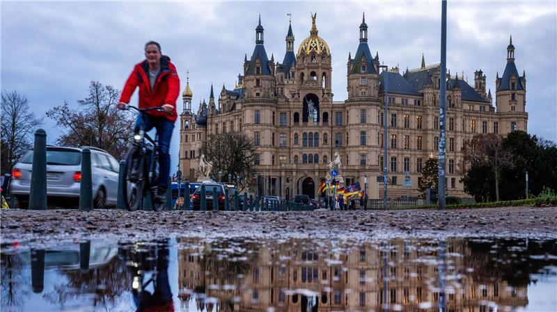 Fahrradfahrer vor dem Schweriner Schloss bei mildem, grauem Wetter in Norddeutschland.