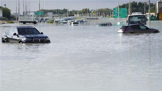 Fahrzeuge stehen verlassen im Hochwasser auf einer Hauptstraße in Dubai.