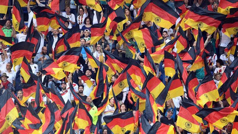 Fans schwenken Deutschlandfahnen auf der Tribüne.