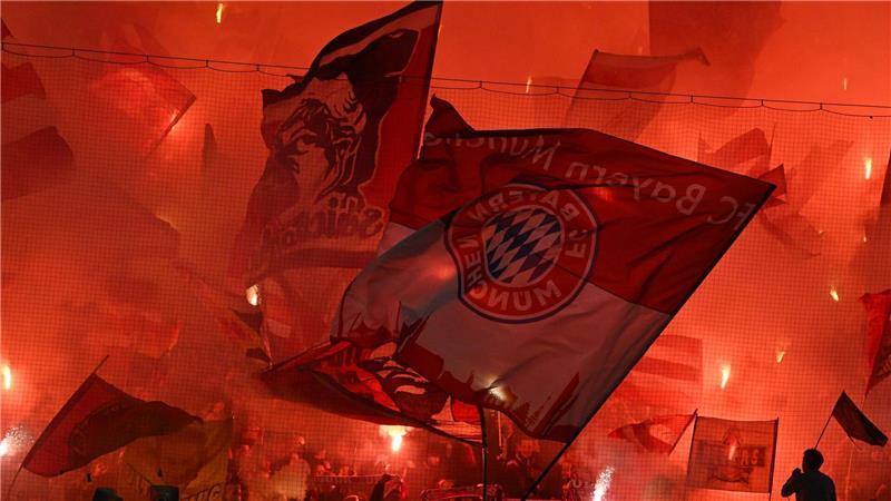 Fans schwenken Fahnen auf der Tribüne beim Spiel Bayern München gegen Bayer Leverkusen in der Champions League,