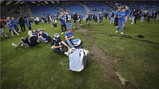 Fans sitzen auf dem Rasen und feiert den Aufstieg in die 1. Bundesliga. 