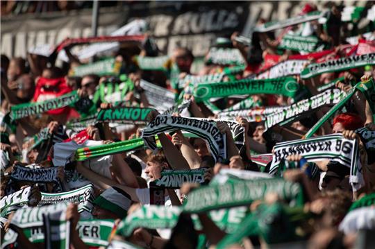 Fans von Hannover 96 feiern auf der Tribüne.