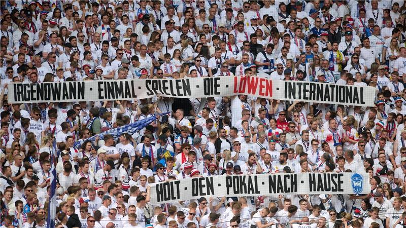 Mit Stolz und Fanparty: Holstein Kiels Bundesliga-Abschied Fans von Holstein Kiel mit einem Banner im Stadion: „Irgendwann einmal spielen die Löwen international - Holt den Pokal nach Hause“.
