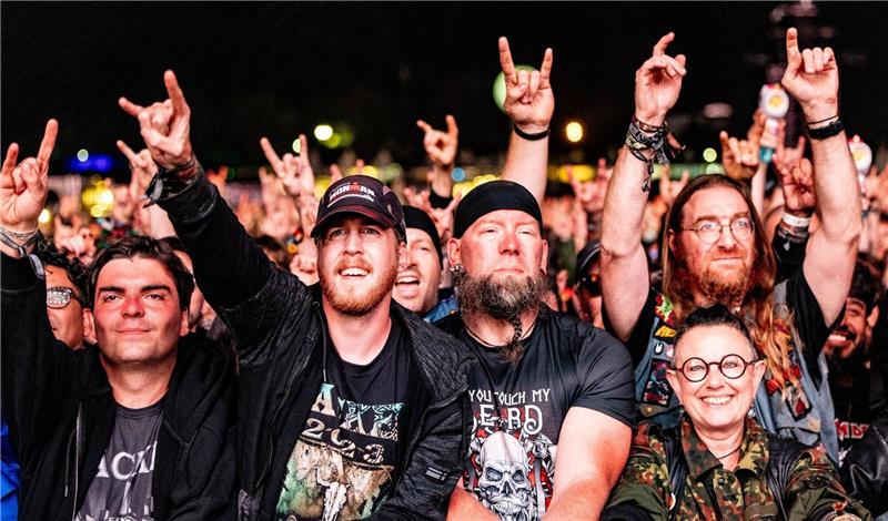 Festivalbesucher feiern vor einer Bühne die auftretenden Musiker.