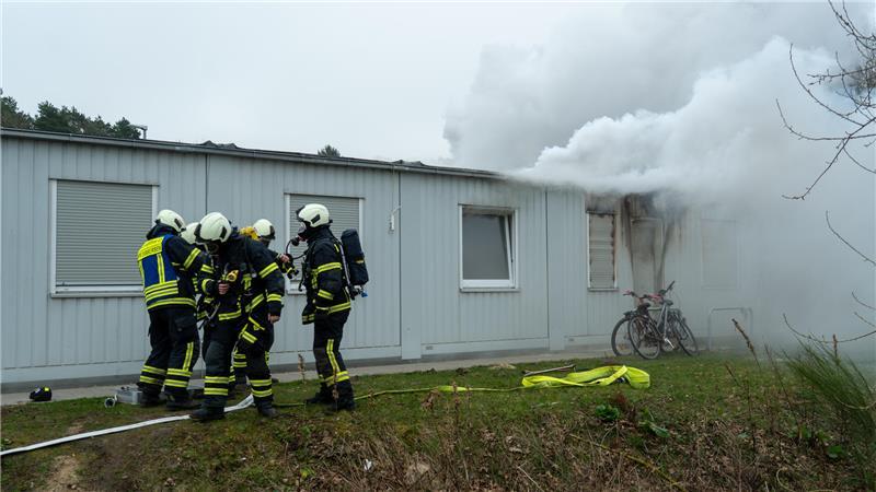 Feuerwehrkräfte bekämpfen die Flammen im Wohncontainer.