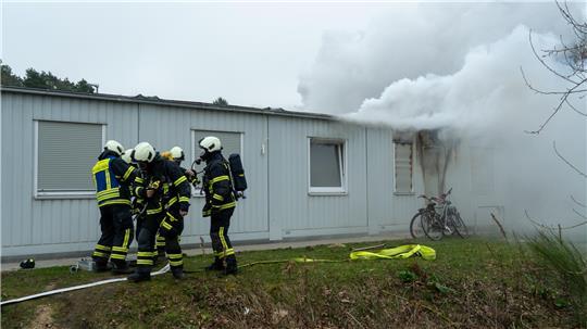 Feuerwehrkräfte bekämpfen die Flammen im Wohncontainer.