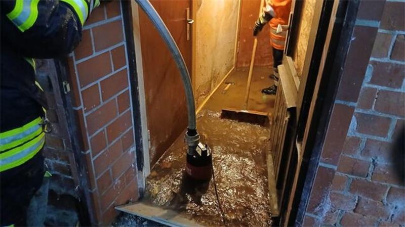 Feuerwehrkräfte pumpen nach dem Starkregen in Hemmoor Wasser aus einem vollgelaufenen Keller.