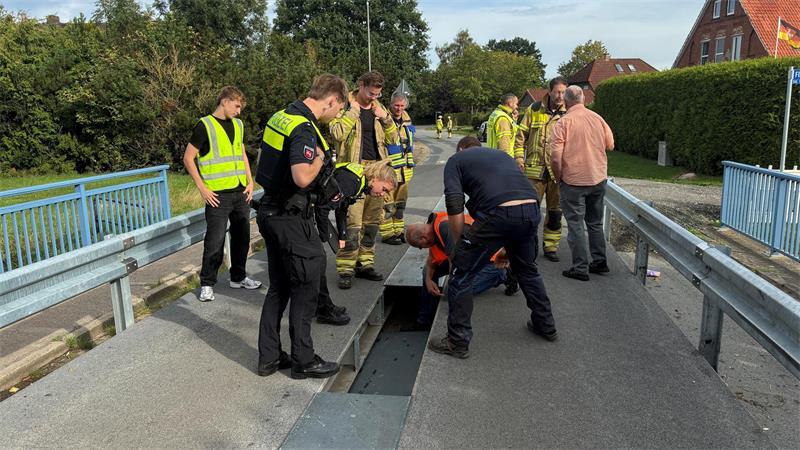 Feuerwehrleute, Polizisten und Mitarbeiter der Kommunale Betriebe Stade blicken auf das Loch in der Brücke über den Bützflether Kanal.