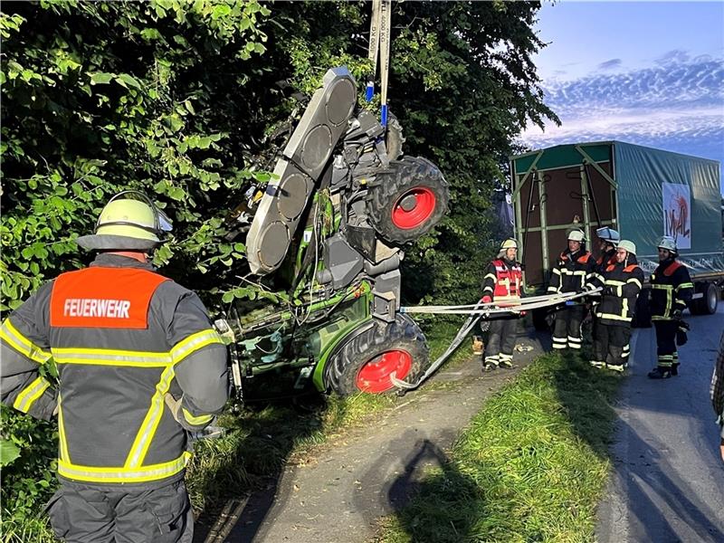 Feuerwehrleute bergen das Schlepper-Gespann mithilfe eines Baggers an der L140 in Hollern. Foto: Vasel