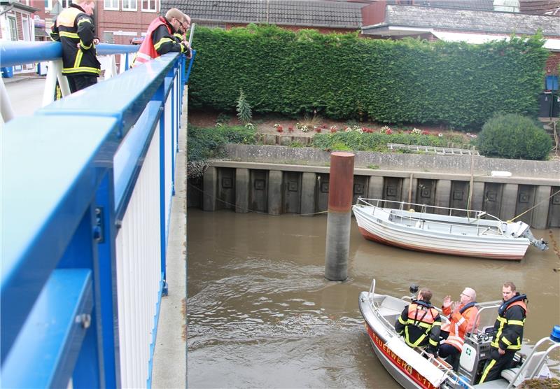 Feuerwehrleute betrachten von der Estebücke und vom Boot aus die in der Flussmitte treibende, gut 1,5 Kilometer lange Ölspur . Foto Richter