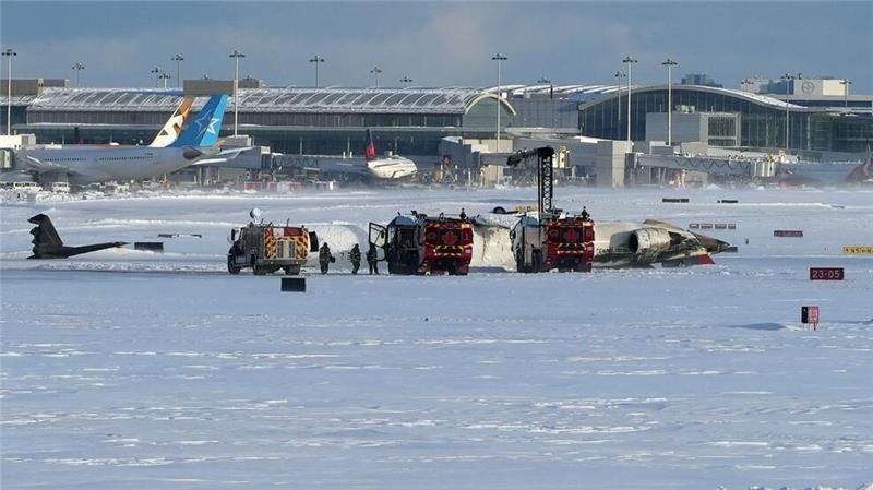 Feuerwehrleute des Toronto Pearson International Airport arbeiten an einem auf dem Rücken liegenden Flugzeug der Delta Air Lines.