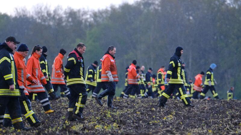 Feuerwehrleute laufen über einen Acker nahe Bremervörde.