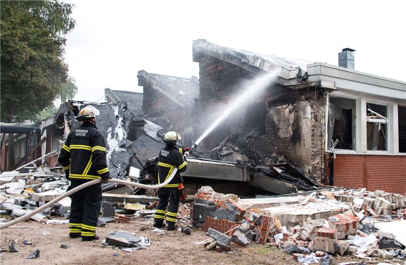 Feuerwehrleute löschen Trümmer eines Gebäudes der Stadtteilschule Finkenwerder. An der Schule hat es in der vergangenen Nacht einem Großbrand gegeben, Menschen wurden dabei nicht verletzt. Foto: Daniel Bockwoldt/dpa