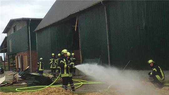 Feuerwehrleute löschen einen Scheunenbrand.