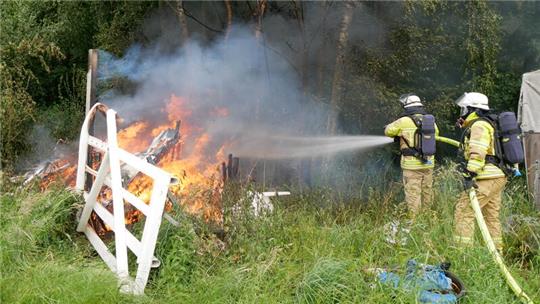 Feuerwehrleute löschen den brennenden Schuppen.