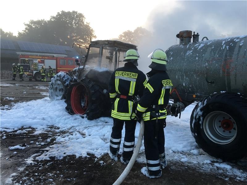 Feuerwehrleute löschen den brennenden Traktor. Foto: Beneke