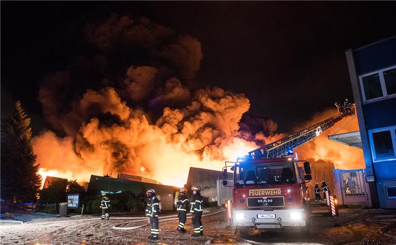 Feuerwehrleute löschen im Stadtteil Wilhelmsburg ein Großbrand. Eine Lagerhalle in einem Gewerbegebiet steht seit dem Morgen im Vollbrand. Foto: Daniel Bockwoldt/dpa