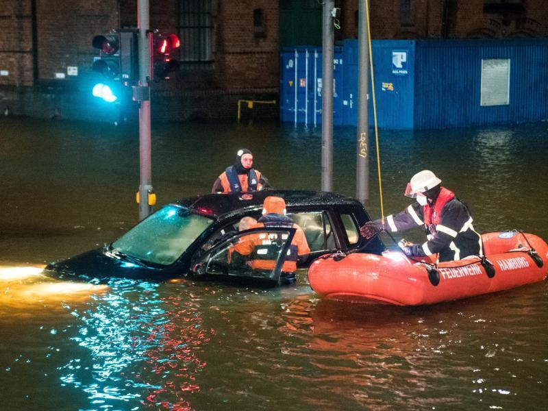 Feuerwehrleute retten in Hamburg einen Mann aus seinem Auto. Foto: Daniel Bockwoldt/dpa