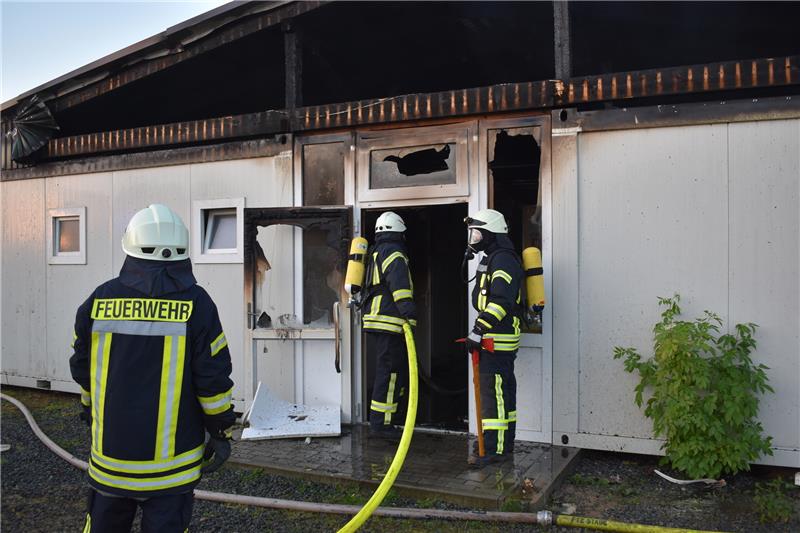 Asyl-Unterkunft in Deinste durch Feuer zerstört Feuerwehrleute rücken unter Atemschutz erneut in das Gebäude vor, der Dachbereich wurde mit Hilfe eines Radladers vorher geöffnet. Foto: Vasel
