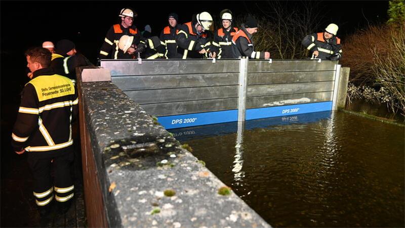 Feuerwehrleute schließen das Deichschart in Guderhandviertel/Neuhof an der Lühe.