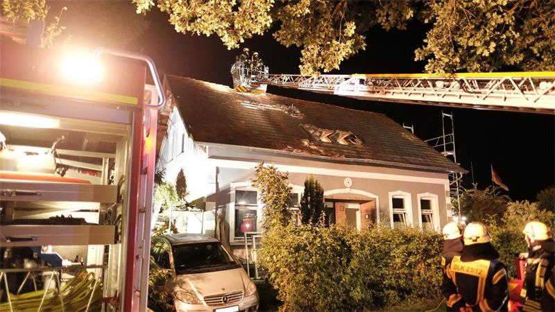 Feuer frisst sich durchs Holz – Hoher Schaden in Estorf Feuerwehrleute sid auf Drehleiter am Dach im Einsatz.
