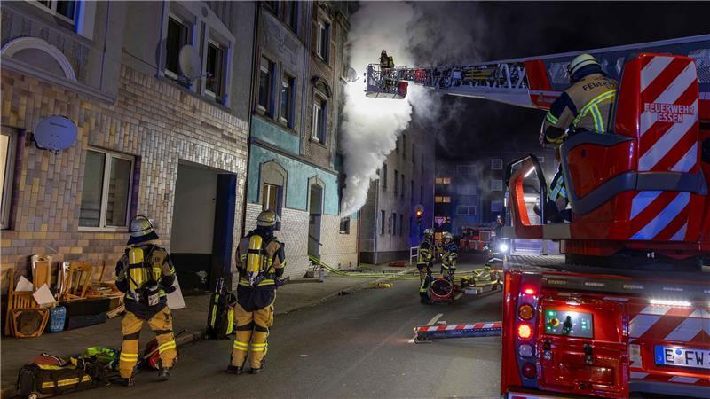 Feuerwehrleute sind u.a. mit einer Drehleiter damit beschäftigt, einen Brand in einem Wohnhaus in Essen zu bekämpfen.