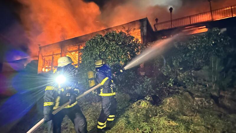 Harburger Hotel steht in hellen Flammen - 100 Einsatzkräfte vor Ort Feuerwehrleute sprühen Wasser in die Flammen eines Brandes in einem leerstehenden Hotel.
