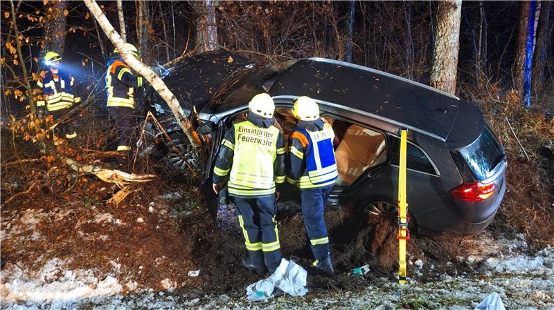 Feuerwehrleute stehen am verunfallten Pkw.