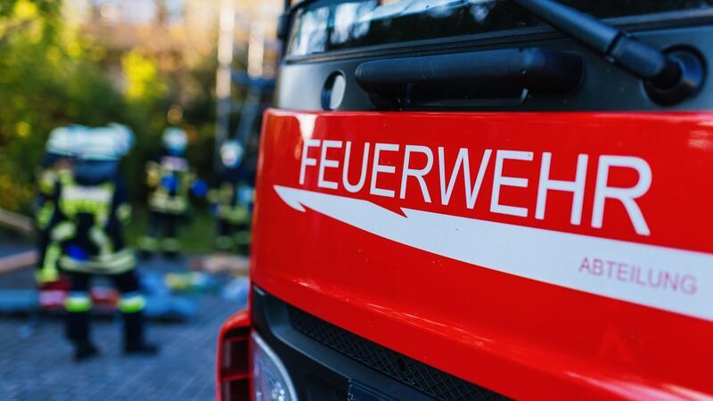 Feuerwehrleute stehen hinter einem Einsatzfahrzeug.