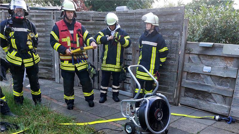 Rauchalarm in Gräpel – 63 Feuerwehrleute rücken an Feuerwehrleute stehen mit einem Überdrucklüfter im Gräpeler Garten.