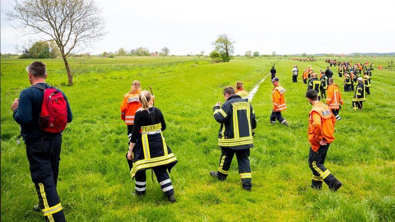 Feuerwehrleute suchen mit einer Menschenkette auf einem Feld nach dem vermissten sechs Jahre alte Arian aus Elm.