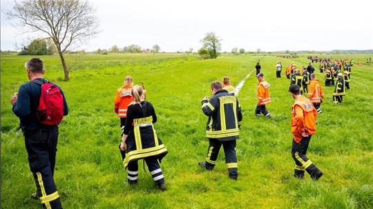 Feuerwehrleute suchen mit einer Menschenkette auf einem Feld nach dem vermissten sechs Jahre alte Arian aus Elm.