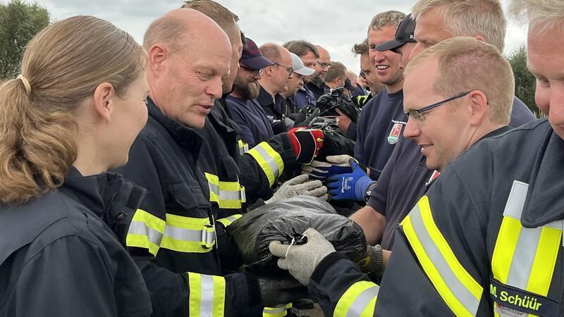 Katastrophenschützer proben Ernstfall an der Elbe Feuerwehrleute tragen Sandsäcke auf den Deich.