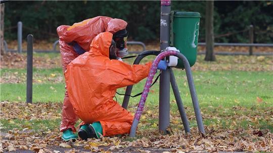 Tasche im Müll: unbekannte Substanz nicht radioaktiv Feuerwehrleute überprüfen eine Mülltonne.