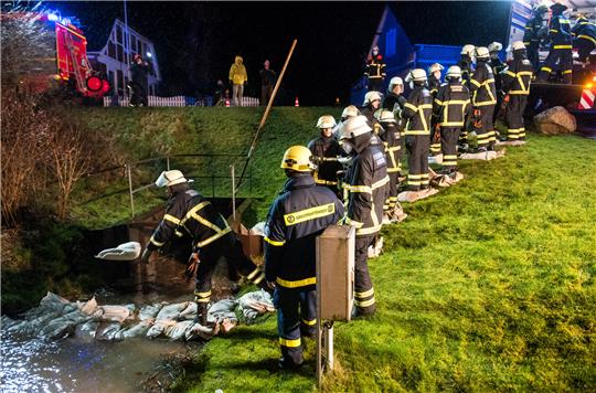 Feuerwehrleute und Helfer des THW verlegen im Hamburger Stadtteil Curslack Sandsäcke an einem Graben an der Dove-Elbe, um Wohnhäuser vor Hochwasser zu schützen. Foto: Daniel Bockwoldt/dpa
