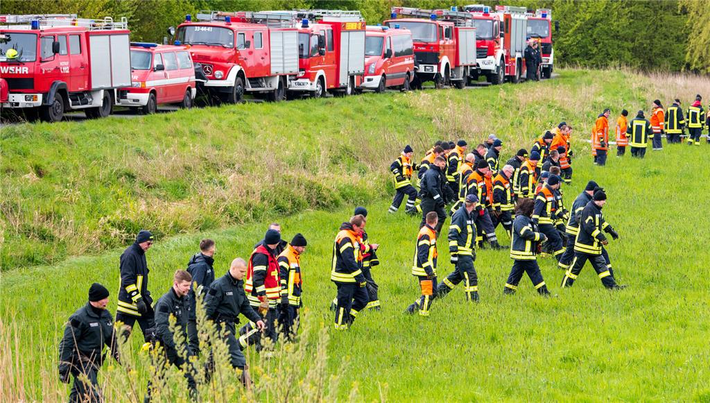 Feuerwehrleute und Polizisten suchen auf einem Feld in Kranenburg.
