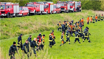 Feuerwehrleute und Polizisten suchen auf einem Feld in Kranenburg.