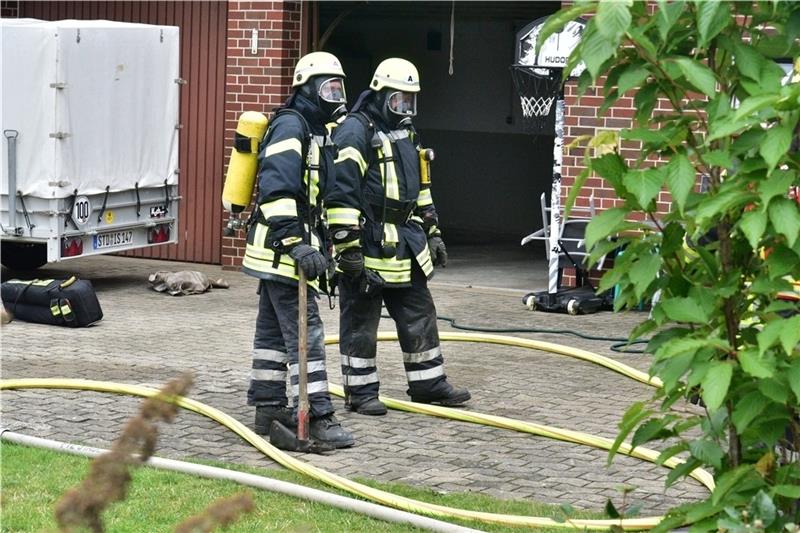 Feuerwehrleute unter schwerem Atemschutz bereiten sich auf den Einsatz im Keller des Wohngebäudes vor. Foto: Beneke