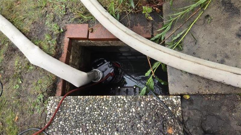 Feuerwehrschläuche führen in einen überfluteten Schacht: Nach dem Starkregen pumpten Einsatzkräfte in Hemmoor Wasser aus Kellern, Häusern und Abwasserschächten.