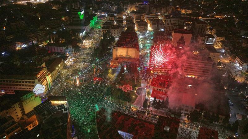Feuerwerk erhellt den Himmel, während die Menschen den Clock Square in der syischen Stadt Homs anlässlich des ersten Jahrestags des Sturzes des Regimes von Bashar Assad füllen.