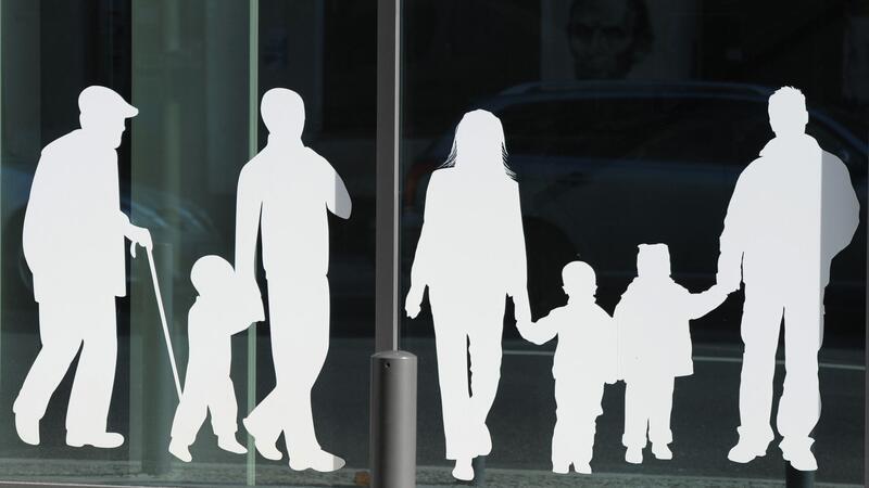 Figuren von Menschen in verschiedenem Alter sind auf Fensterscheiben aufgeklebt.