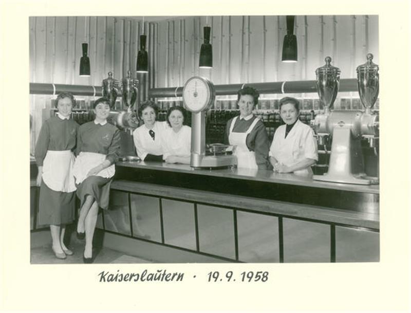 Vom Kaffeeröster zum Gebrauchswarenhändler – Tchibo wird 75 Filial-Mitarbeiterinnen von Tchibo in Kaiserslautern 1958 mit Mühlen und Waage. Im Hintergrund stapeln sich die 250g Päckchen Gold Mocca.