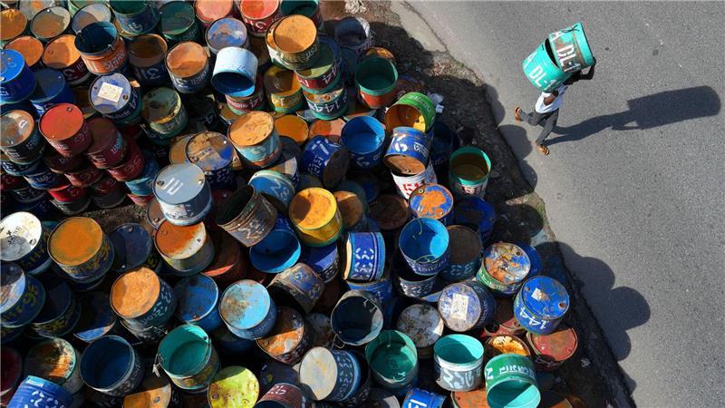 Bilder des Tages Fisch in bunten Dosen: Arbeiter im Bezirk Rangamati in Bangladesch tragen Metallfässer, die für den Transport von Fisch verwendet werden.