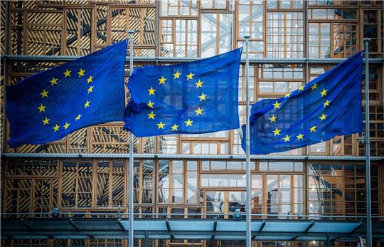 Flaggen der Europäischen Union vor dem Europa-Gebäude in Brüssel. Die Wirtschaft in der EU wird in diesem Jahr nach einer Prognose der EU-Kommission langsamer wachsen als zuletzt erwartet.