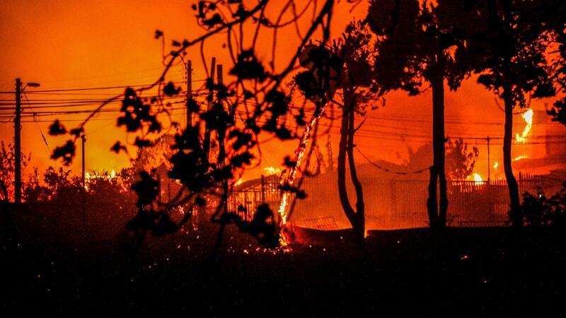 Flammen und Rauch sind zu sehen, als Häuser während eines Waldbrandes in Chile niederbrennen.