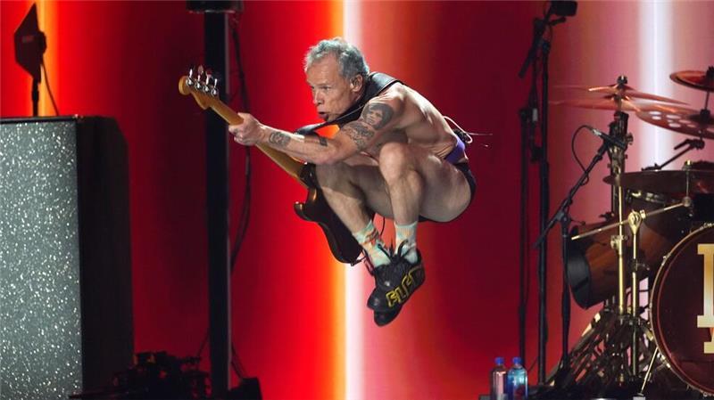 Flea von den Red Hot Chili Peppers macht Luftsprünge. 